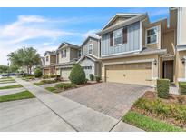 Charming townhomes with two-car garages and brick paver driveways under a bright blue sky at 1262 E 10Th St, Apopka, FL 32703