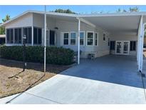 Well-maintained single-story home featuring a covered carport and enclosed sunroom, nestled amongst mature shrubs at 158 Rita Bee Ave, Davenport, FL 33897