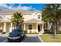 Charming two-story yellow townhome featuring a well-maintained front lawn and covered front porch at 17419 Placidity Ave, Clermont, FL 34714
