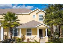 Inviting two-story townhome features a charming covered entryway, two chairs, and lush tropical landscaping at 17419 Placidity Ave, Clermont, FL 34714