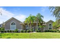Beautiful single-story home with a well-manicured lawn, palm trees, and lovely landscaping at 2232 Lake Vilma Dr, Orlando, FL 32835