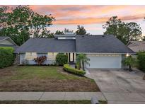 Charming single story home featuring a landscaped front yard, attached two-car garage, and a beautiful sunset sky at 2260 Winslow Cir, Casselberry, FL 32707