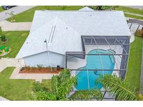 Aerial view of a screened-in pool and a well maintained lawn with tropical landscaping at the rear of the home at 2369 Haulover Blvd, Deltona, FL 32738