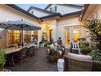 A gorgeous outdoor patio features stylish seating, dining, and decor with accent lighting and lush greenery at 3883 Grassland Loop, Lake Mary, FL 32746