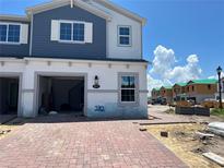 Newly constructed two-story townhome with a brick driveway, an attached garage, and blue and white siding at 4271 Campsite Loop, Orlando, FL 32824