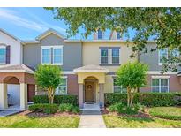 Inviting townhome with a well manicured lawn and a charming entryway with a decorated front door and green bushes at 7819 Hardenton St, Windermere, FL 34786