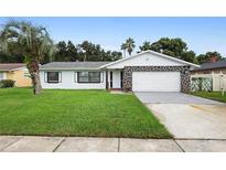Charming one-story home with stone detail, green lawn, and mature palm tree at 10140 Bridlewood Ave, Orlando, FL 32825