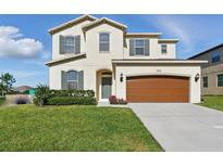 Charming two-story home with a well-maintained lawn, a two-car garage, and attractive architectural details at 1018 Boxelder Ave, Minneola, FL 34715
