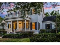Charming two-story home featuring a welcoming front porch and balcony, complemented by lush landscaping and inviting curb appeal at 1106 Celebration Ave, Celebration, FL 34747