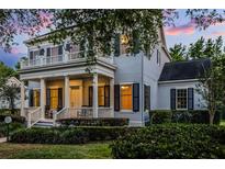 Charming two-story home featuring a covered porch, balcony, and manicured landscaping at sunset at 1106 Celebration Ave, Celebration, FL 34747