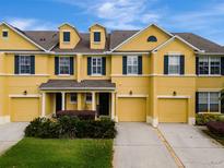 Inviting yellow townhome features multiple dormers, green shutters, and well-maintained landscaping at 1570 Barking Deer Cv, Casselberry, FL 32707