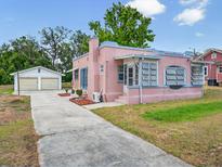 Charming pink home featuring unique architectural details and a detached two-car garage at 16 E Orange Street St, Davenport, FL 33837