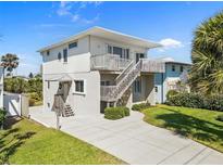 Two-story home with a light-colored exterior, complemented by a wooden staircase leading to a private upper-level balcony at 1640 N Atlantic Ave, New Smyrna Beach, FL 32169