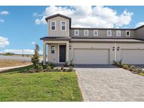 New two-story townhome featuring a gray exterior, a two-car garage, and a beautiful lawn with green grass at 1805 Archer Dr, Minneola, FL 34715