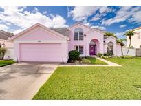 Charming pink two-story home with a well-manicured lawn and a two-car garage at 2712 Rolling Broak Dr, Orlando, FL 32837