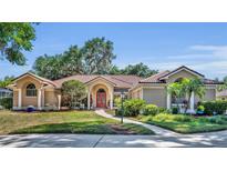 Stunning single-story home with a red front door, mature trees, and lush landscaping in a well-kept lawn at 605 W Palm Valley Dr, Oviedo, FL 32765