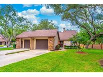 Charming home exterior featuring a well-manicured lawn, mature trees, and a two-car garage at 103 Golf Club Dr, Longwood, FL 32779