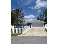 Charming single-story home with a two-car garage, white picket fence, blue exterior, and well-maintained lawn at 11 Pecan Run Ct, Ocala, FL 34472