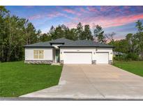 Beautiful single-story home with a well-manicured lawn and a spacious two-car garage at 13068 Sw 36Th Ct, Ocala, FL 34473