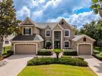 Elegant two-story home with a three-car garage, manicured landscaping and a paver driveway at 14003 Hampshire Bay Cir, Winter Garden, FL 34787