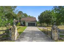 Charming single-Gathering home with a long driveway, mature trees and a welcoming stone and wood fence at 21343 Reindeer Rd, Christmas, FL 32709