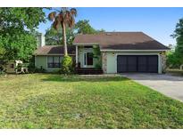Charming single-story home with a lush green lawn, mature trees, and a two-car garage at 21343 Reindeer Rd, Christmas, FL 32709