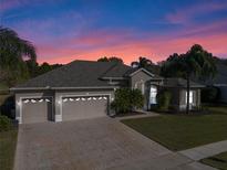 Exterior of a single-Gathering home that has a three-car garage, mature trees, and a large driveway at 23533 Valderama Ln, Sorrento, FL 32776