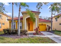 Charming single-Gathering home featuring a red tile roof, yellow garage, and mature palm trees at 1031 Marcello Blvd, Kissimmee, FL 34746