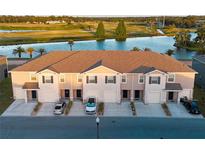 Exterior of townhomes featuring garages, driveways, neutral stucco, and picturesque water views at 1089 Blue Jay Dr, Davenport, FL 33837