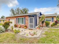 Charming brick home featuring a landscaped front yard and covered porch with decorative accents and a welcoming entrance at 1105 Tivoli Drive, Deltona, FL 32725