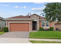 Charming single-story home featuring a stone facade, two-car garage, and well-maintained landscaping at 125 Silver Maple Rd, Groveland, FL 34736