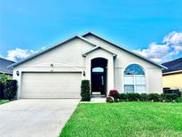 Charming single-story home with an attached two-car garage, arched entry, and manicured landscaping at 128 Brushcreek Dr, Sanford, FL 32771