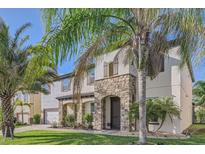 Beautiful two-story home with stone accents, a manicured lawn, and lush landscaping with mature palm trees at 15465 Heron Hideaway Cir, Winter Garden, FL 34787