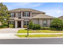 Charming two-story home with a well-manicured lawn, beautiful landscaping, and a paved driveway at 15485 Sandfield Loop, Winter Garden, FL 34787