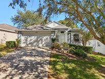 Charming single-story home with a two-car garage, well-manicured landscaping, and mature shade trees at 2302 Edmonton Ct, Clermont, FL 34711