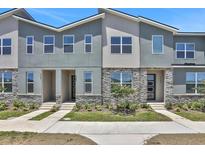 Exterior shot of modern townhouses with stone accents, contemporary design, and manicured landscaping at 2382 Zaballina Pl, Kissimmee, FL 34747