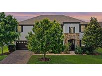 Beautiful two-story home with a stone-accented entrance, lush landscaping, and a paver driveway at 408 Egret Place Dr, Winter Garden, FL 34787