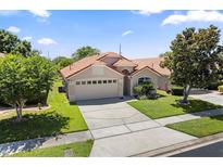 Charming single-story home featuring a two-car garage, beautiful landscaping, and a classic tile roof at 5337 Watervista Dr, Orlando, FL 32821
