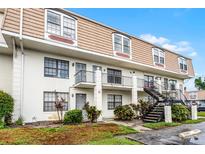 Three-story apartment building featuring a staircase and landscaping at 6095 Village Cir # 6095, Orlando, FL 32822