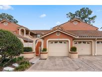 Charming townhome with terra cotta exterior, tile roof, and attached garages with garden pots adding curb appeal at 7449 Sugar Bend Dr # 7449, Orlando, FL 32819