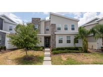 Contemporary two-story home featuring a stone facade, well-manicured lawn, and modern architectural details at 780 Drop Shot Dr, Davenport, FL 33896