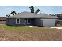 Charming one-story home featuring a gray exterior, attached garage, and well-manicured lawn at 15164 Sw 46Th Cir, Ocala, FL 34473
