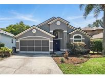 Charming single-story home featuring a gray facade, manicured lawn, and a two-car garage at 2611 Burwood Ave, Orlando, FL 32837