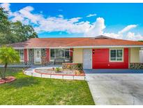 Charming home featuring stone accents, a red exterior, and a well-maintained landscaped front yard at 898 Hendry Dr, Orlando, FL 32822