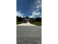Charming single-story home with a well-manicured lawn and a paved driveway leading to an attached garage at 9028 Se 41St Court Rd, Ocala, FL 34480