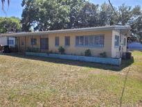 Charming single-story home with a covered porch, light yellow paint, and verdant landscaping at 936 Pinedale Ave, Orlando, FL 32808