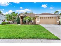 Charming tan home featuring a lush green lawn, manicured landscaping, and a two-car garage in a quiet neighborhood at 1585 Maidencane Loop, Oviedo, FL 32765