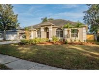 Well-manicured lawn leads to a single-story home with arched windows and a neutral color palette at 4837 Lorraine Way, Orlando, FL 32812