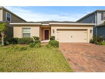 Charming single-story home featuring a two-car garage and brick paved driveway at 714 Golden Elm Dr, Apopka, FL 32703