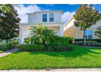 Well-maintained front yard with lush green lawn, colorful bushes and landscaped garden beds at this lovely two-story home at 11386 Biography Way, Orlando, FL 32832